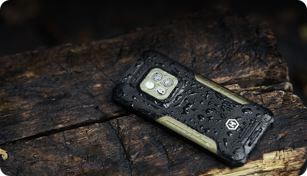 HAMMER CONSTRUCTION 2 THERMAL 5G Military Edition leżący na drewnie; krople wody na obudowie