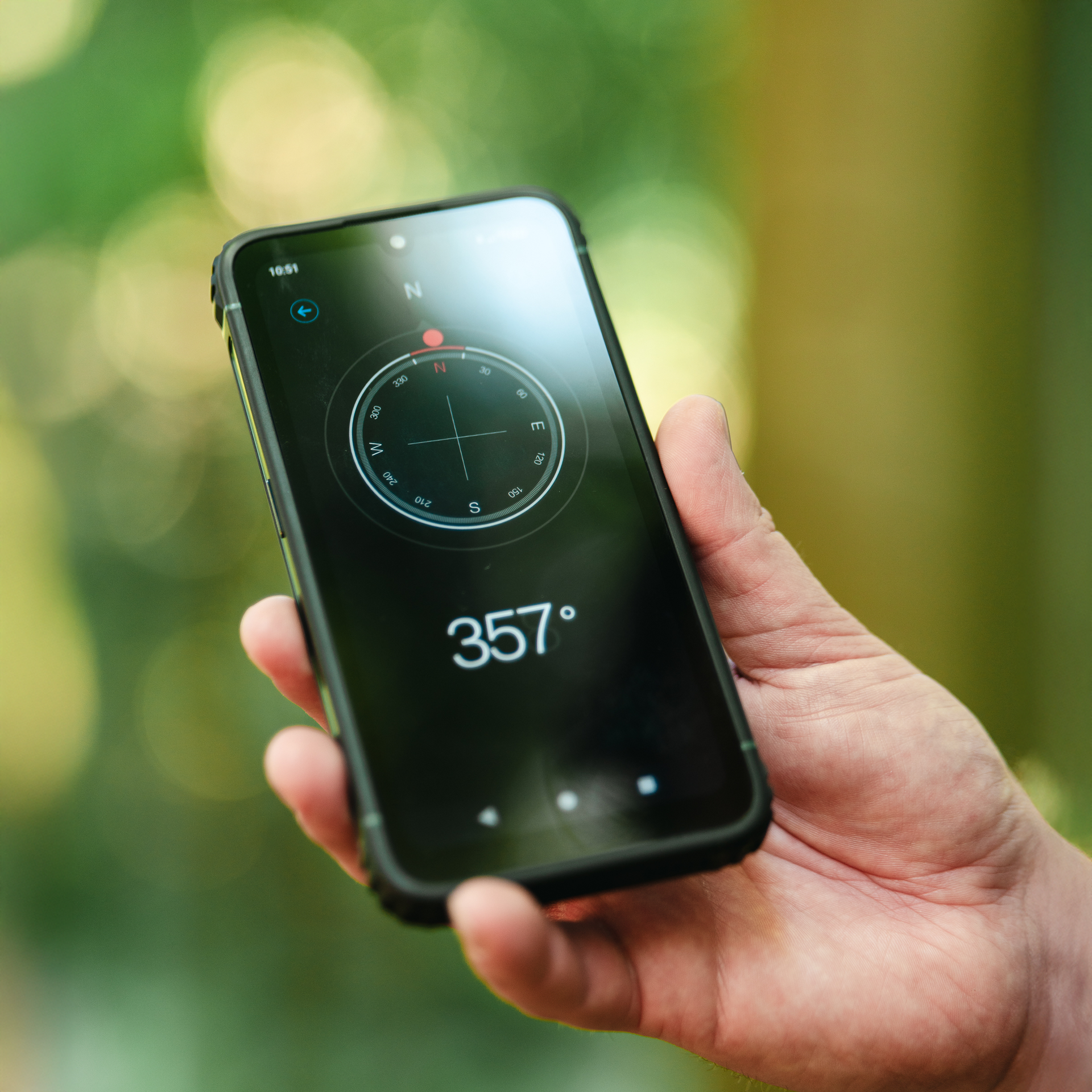Smartfon HAMMER RANGER w dłoni; na ekranie aplikacja kompasu