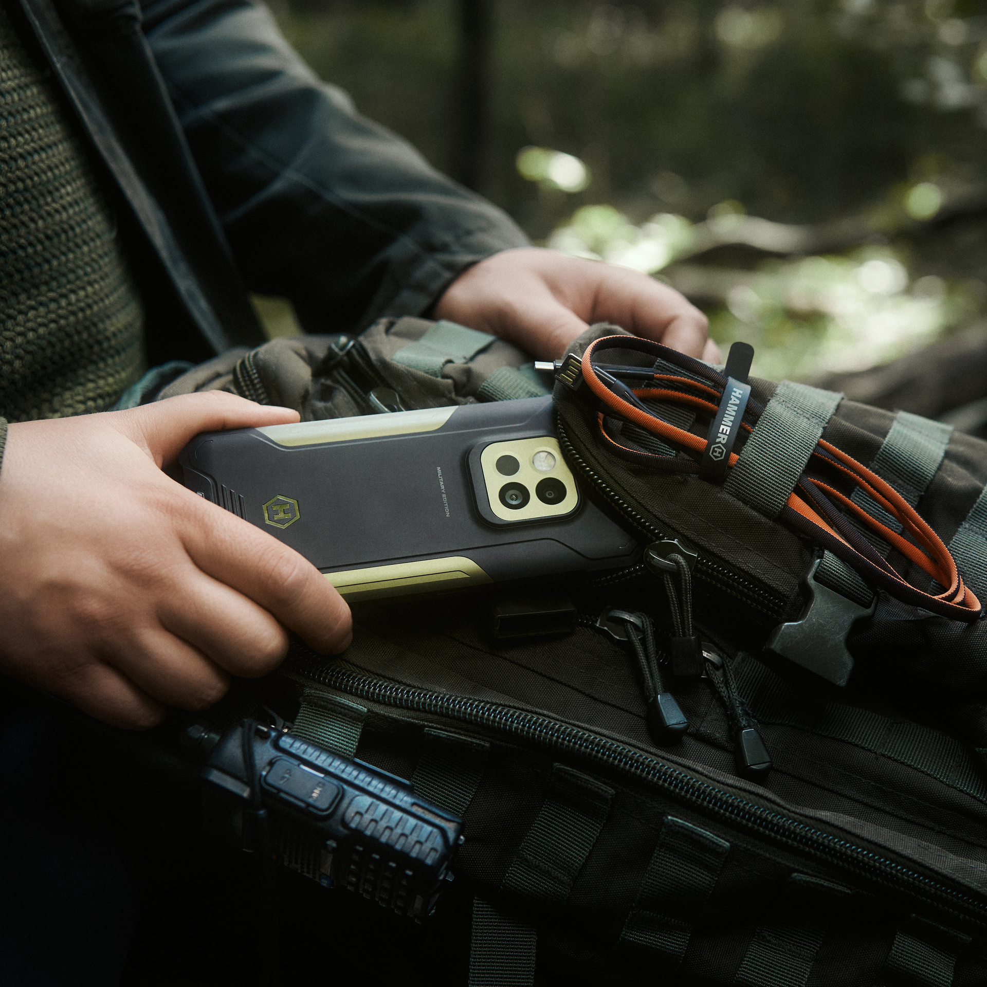 Dłoń wkłada do plecaka HAMMER CONSTRUCTION 2 5G MILITARY EDITION i akcesoria