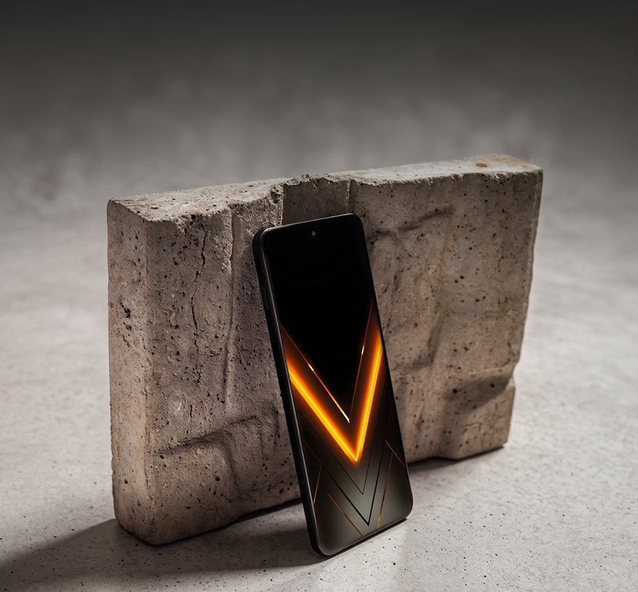 Smartfon HAMMER VENTUS 5G z pomarańczowym motywem V na ekranie, oparty o betonowy blok