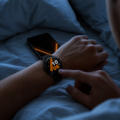 Osoba korzystająca ze smartwatcha HAMMER WATCH VENTUS PRO w łóżku, obok leży smartfon HAMMER VENTUS 5G