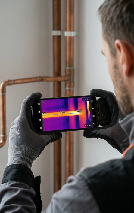 Kamera termowizyjna HAMMER HEAT VIEW podłączona do smartfona podczas pomiaru temperatury miedzianej rury