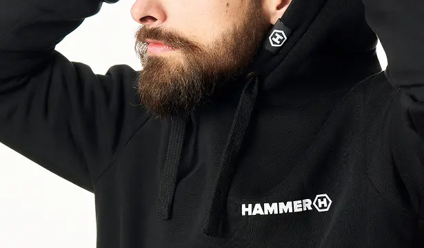 HAMMER HOODIE mężczyzna ubrany w bluzę stoi na białym tle.  Zbliżenie na logo i kaptur.