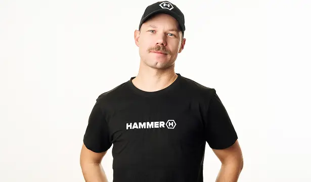 HAMMER T-SHIRT BASIC mężczyzna na białym tle w koszulce i czapce HAMMER.  Uśmiecha się lekko.