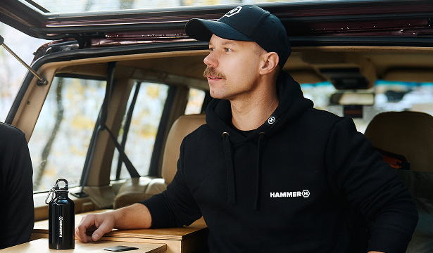 HAMMER Bluza z kapturem  towarzyszy na kempingu. Mężczyzna opiera się o bagażnik auta. 