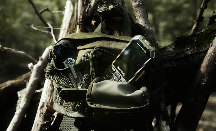 Telefon HAMMER 6 LTE Military Edition w plecaku w lesie.