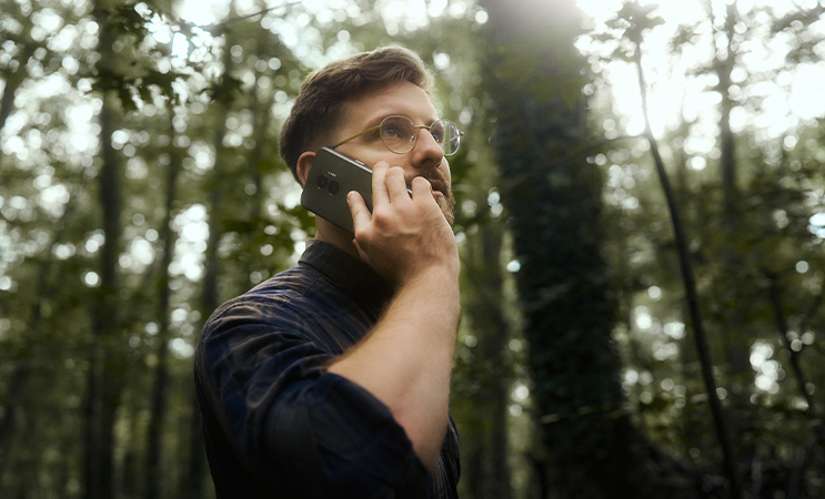 Mężczyzna rozmawiający przez smartfon HAMMER w lesie