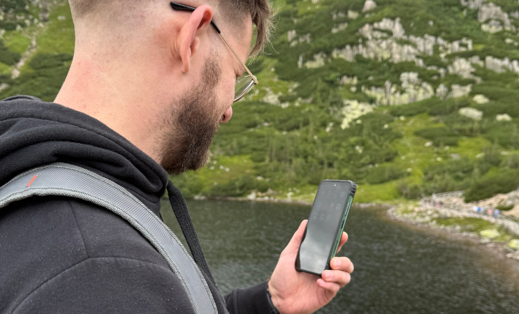 HAMMER Ranger mężczyzna sprawdza telefon nad jeziorem